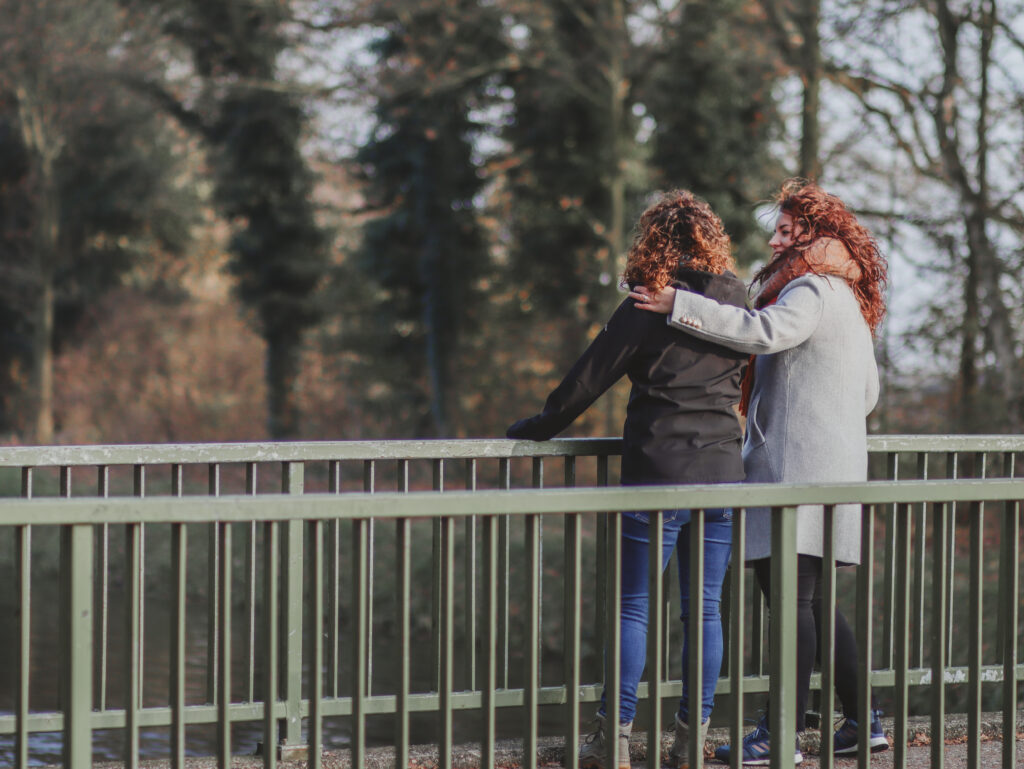 Twee vrouwen op een brug die elkaar steunen.